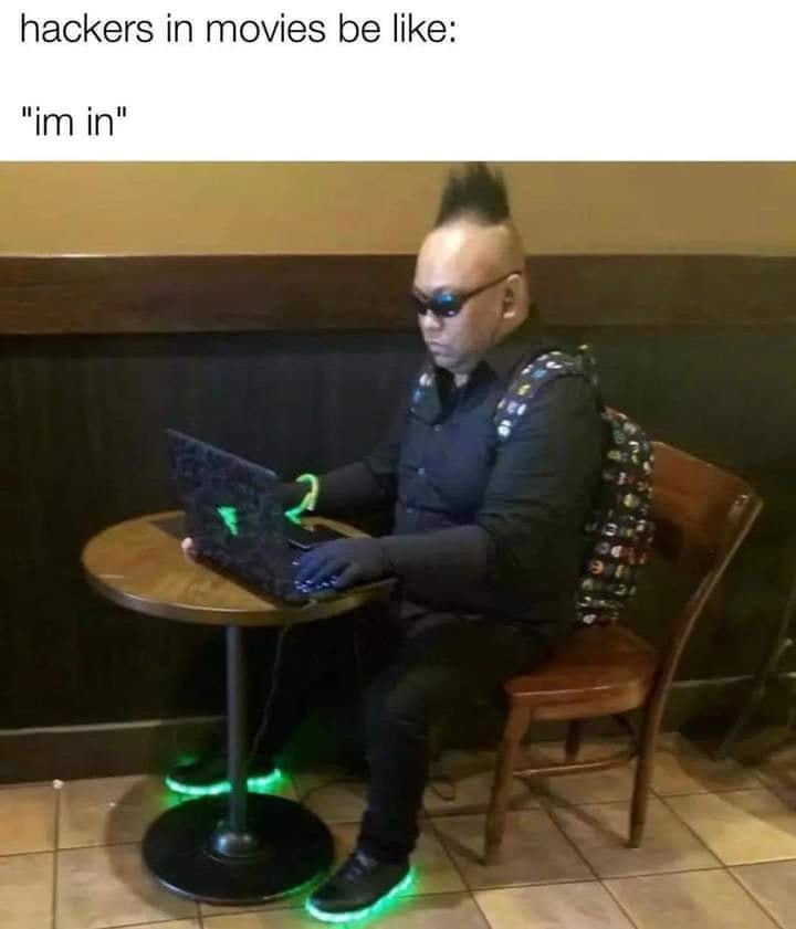 This meme is a humorous image of a person sitting at a table with a laptop, wearing a black outfit and sunglasses. The text at the top of the image reads "hackers in movies are always like" and the text at the bottom reads "but in reality they're just like this guy". The image is meant to poke fun at the common movie trope of hackers being portrayed as cool and tech-savvy, but in reality, they're often just a person sitting at a table with a laptop.